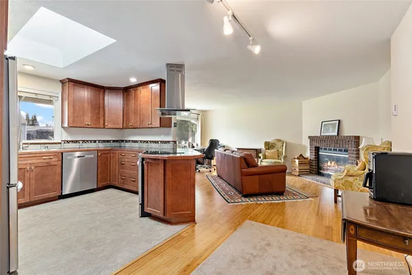 a kitchen with stainless steel appliances granite countertop a stove top oven a sink dishwasher and white cabinets with wooden floor