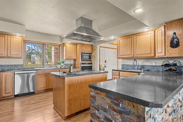 a kitchen with stainless steel appliances granite countertop a stove and a wooden floors