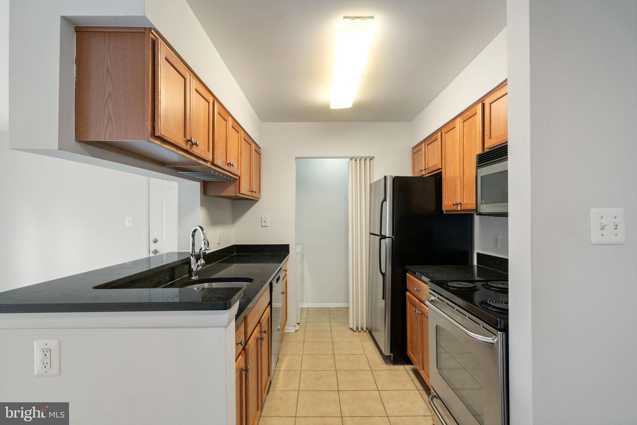 11703 Olde English Drive, Unit B Reston, VA 20190 - Photo 11 of 32 a kitchen with stainless steel appliances granite countertop a sink stove and refrigerator