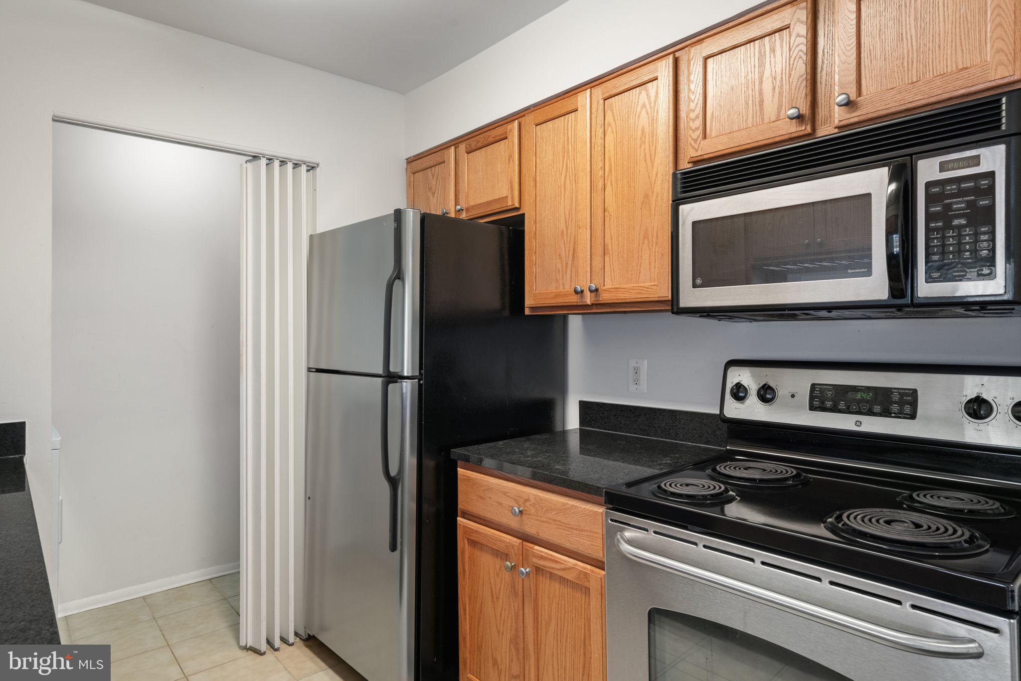 11703 Olde English Drive, Unit B Reston, VA 20190 - Photo 13 of 32 a kitchen with stainless steel appliances granite countertop a refrigerator stove and microwave