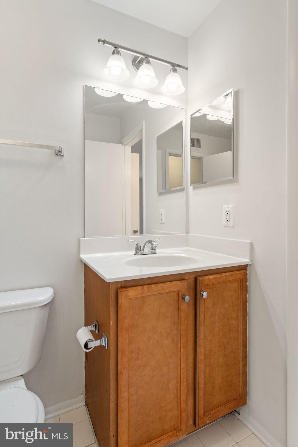11703 Olde English Drive, Unit B Reston, VA 20190 - Photo 25 of 32 a bathroom with a sink a toilet and mirror
