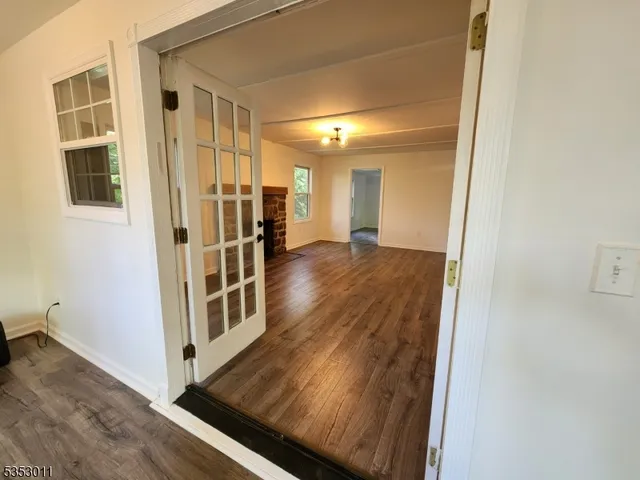 an empty room with wooden floor a fireplace and windows