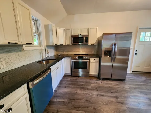 a large kitchen with stainless steel appliances granite countertop a stove a sink and a refrigerator