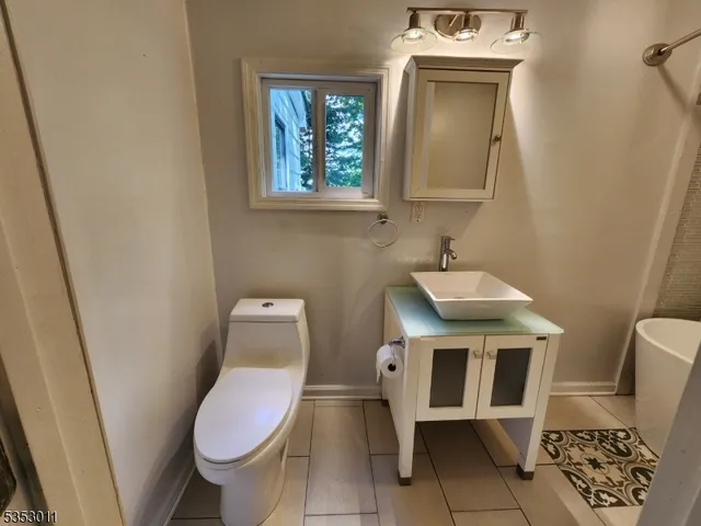 a bathroom with a toilet a sink a mirror and a window