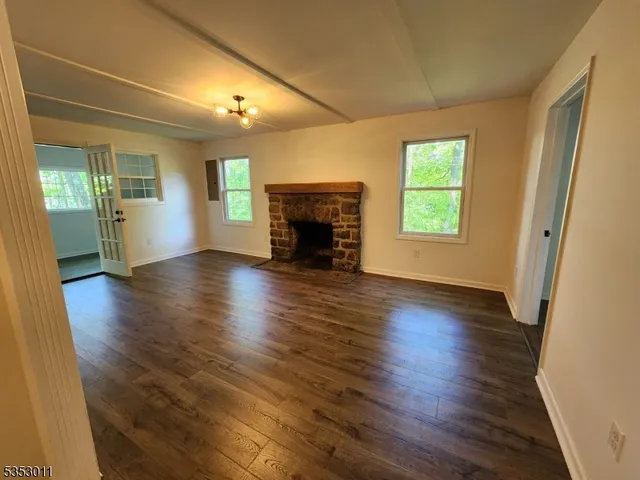 an empty room with wooden floor fireplace and windows