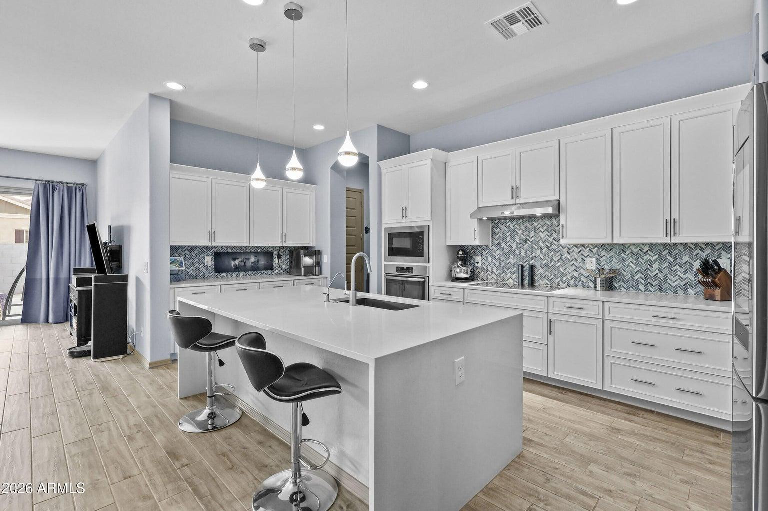 4451 East Bernice Street Gilbert, AZ 85295 - Photo 6 of 32 a large kitchen with stainless steel appliances kitchen island granite countertop a stove a sink a refrigerator and white cabinets with wooden floor