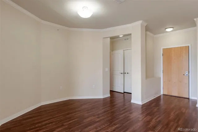 a view of an empty room with wooden floor and closet