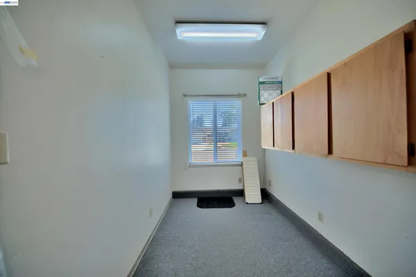 an empty room with a chandelier fan and windows
