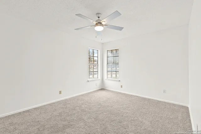 an empty room with windows and fan