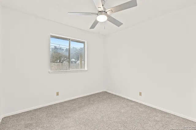 an empty room with a window and a fan