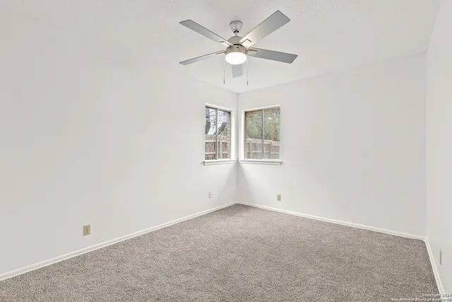 an empty room with windows and fan