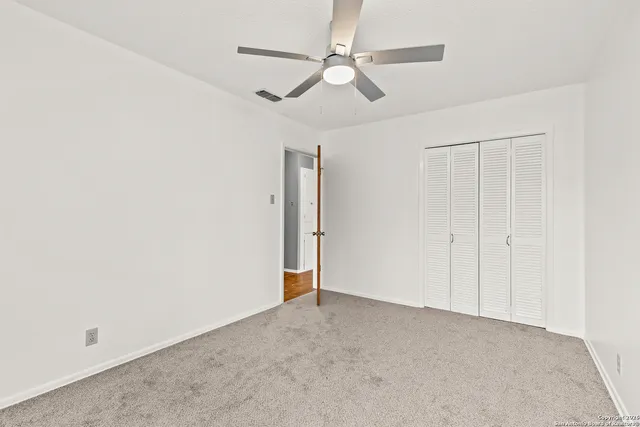 an empty room with a ceiling fan and a window
