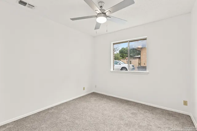an empty room with a window and a fan