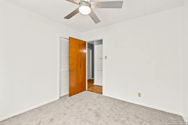 an empty room with a ceiling fan and carpet