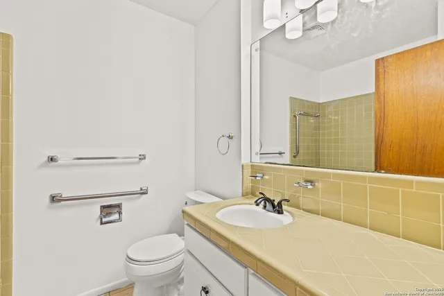 a bathroom with a granite countertop sink a toilet and a mirror