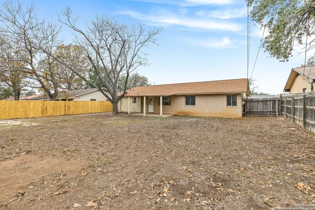 a backyard of a house with large trees and barbeque oven