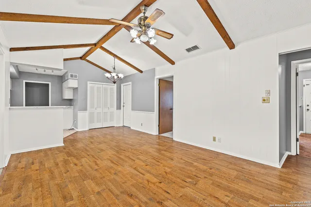 a view of a big room with wooden floor and windows