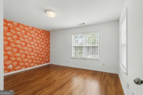 a view of an empty room with a window and wooden floor