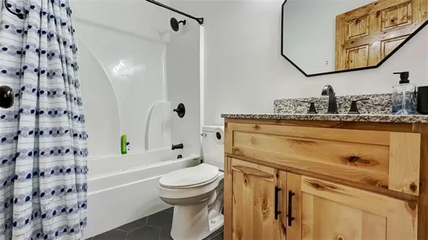 a bathroom with a granite countertop toilet sink and mirror
