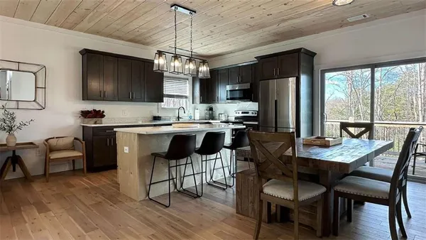 a kitchen with stainless steel appliances kitchen island granite countertop a dining table chairs and refrigerator
