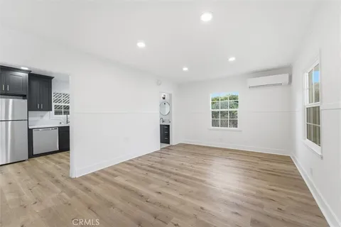 a view of empty room with wooden floor and kitchen view