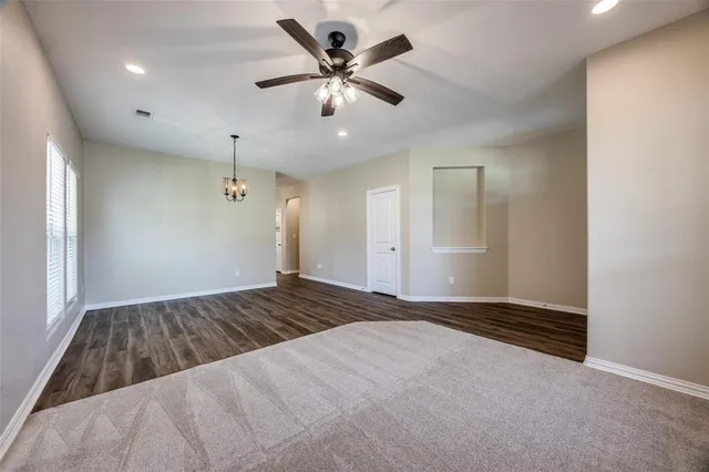 a view of an empty room and chandelier fan