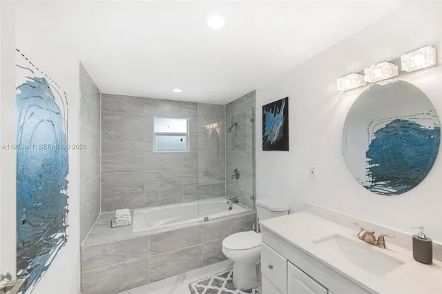 a bathroom with a toilet a sink a mirror a bathtub and shower