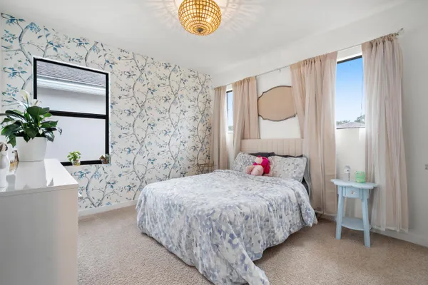 a bedroom with a bed chandelier and a window