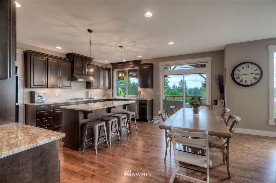 22008 43rd Drive Southeast Bothell, WA 98021 - Photo 8 of 25 a kitchen with stainless steel appliances granite countertop a stove a refrigerator a kitchen island a dining table and chairs with wooden floor