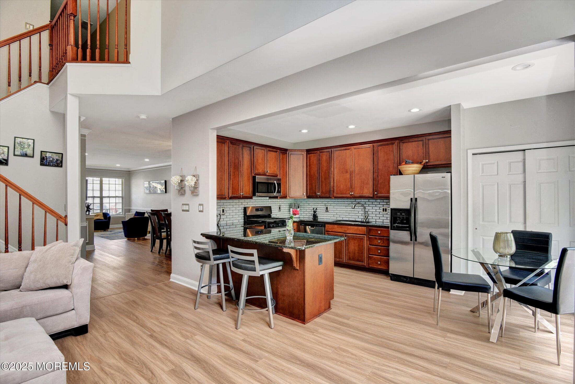 45 Brookfield Drive Jackson, NJ 08527 - Photo 15 of 39 a kitchen with stainless steel appliances granite countertop a refrigerator a stove top oven a dining table and chairs with wooden floor