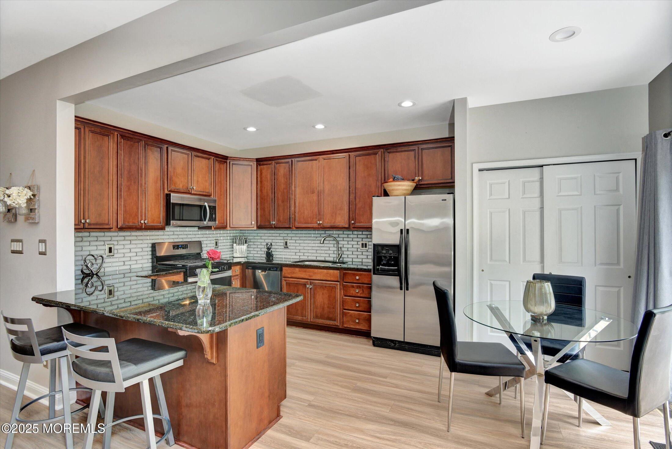 45 Brookfield Drive Jackson, NJ 08527 - Photo 16 of 39 a kitchen with stainless steel appliances granite countertop a stove top oven a sink dishwasher a dining table and chairs with wooden floor