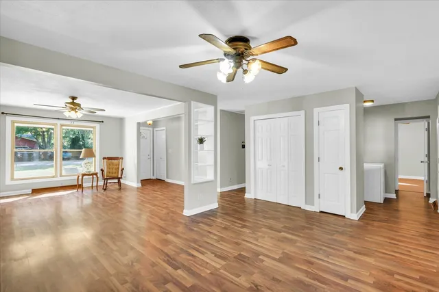 a view of an empty room with window and wooden floor