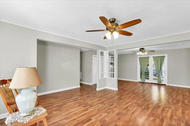a view of an empty room with wooden floor and a ceiling fan