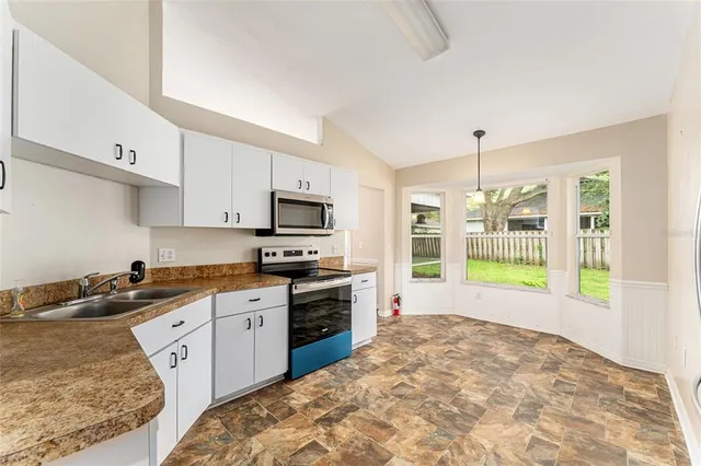 a kitchen with granite countertop white cabinets and stainless steel appliances