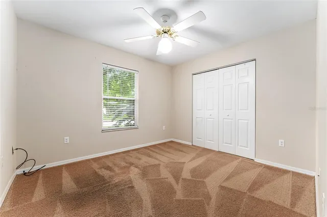 a view of empty room with windows and ceiling fan