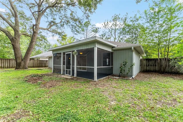 a backyard of a house with plants and large tree