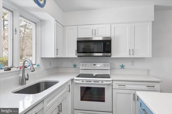 a kitchen with granite countertop a sink a stove and microwave