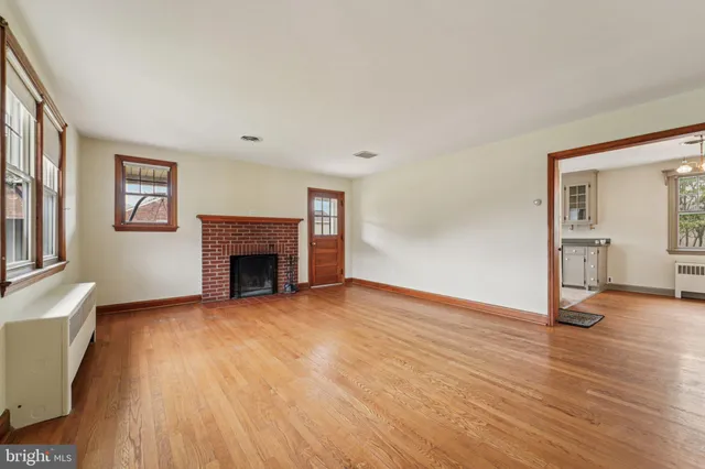 a view of an empty room with wooden floor and a fireplace