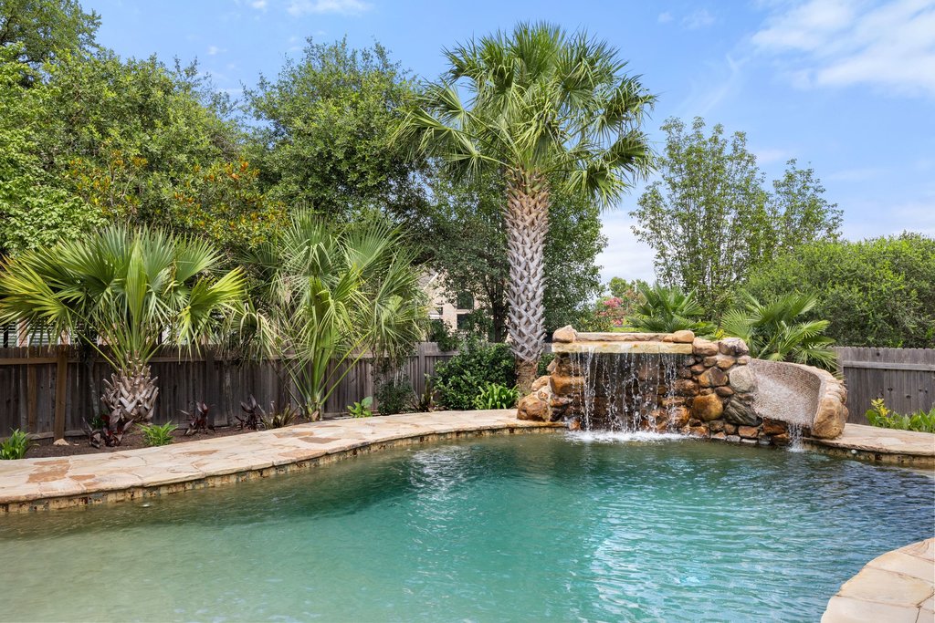 An inviting backyard oasis offers a sparkling in-ground pool with a stone waterfall feature.
