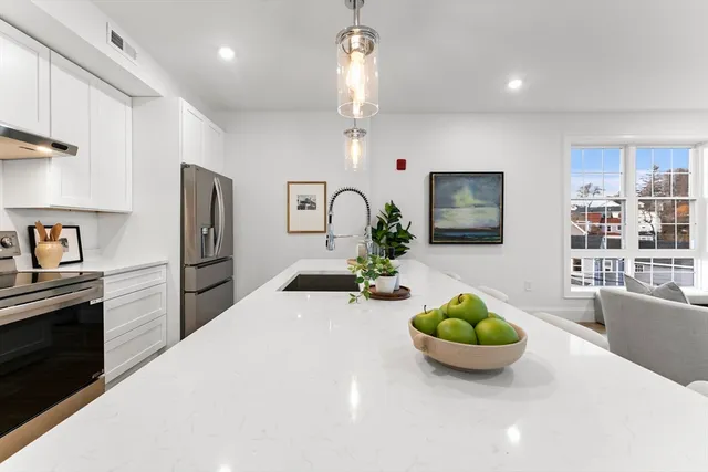 a kitchen with stainless steel appliances a dining table a microwave a refrigerator and cabinets