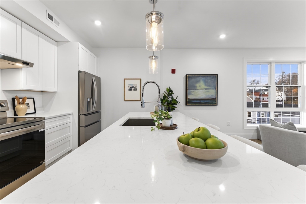 272 Lincoln Street, Unit 301 Marlborough, MA 01752 - Photo 13 of 30 a kitchen with stainless steel appliances a dining table a microwave a refrigerator and cabinets