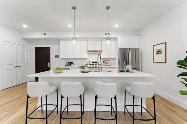 a kitchen with stainless steel appliances a dining table chairs and white cabinets