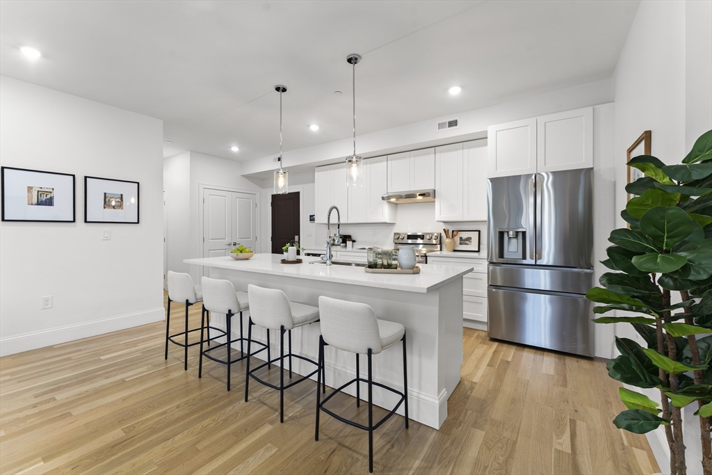 272 Lincoln Street, Unit 301 Marlborough, MA 01752 - Photo 7 of 30 a kitchen with stainless steel appliances a refrigerator a stove a sink dishwasher and a dining table with wooden floor
