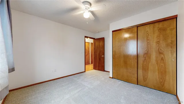 an empty room with closet and a chandelier fan
