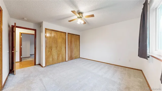 an empty room with closet and a ceiling fan