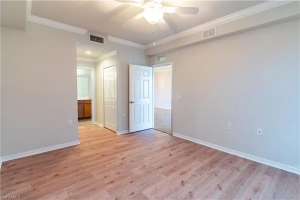 a view of an empty room with wooden floor and a ceiling fan
