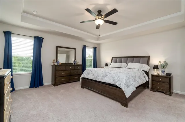 a spacious bedroom with a bed a chandelier and a chair