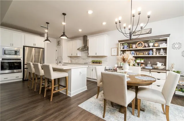 a kitchen with stainless steel appliances kitchen island a dining table and chairs