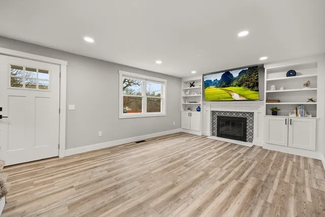 a view of empty room with fireplace and wooden floor