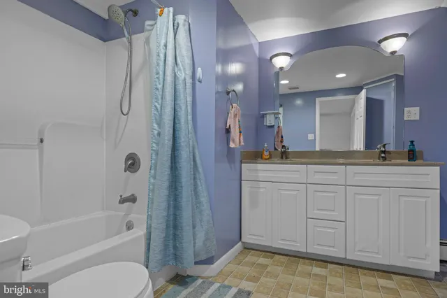 a bathroom with a granite countertop sink a toilet a mirror a vanity and bathtub